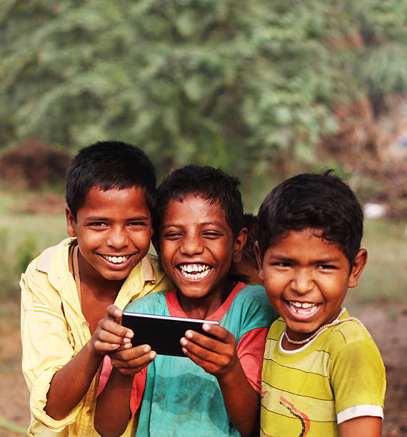 cheerful rural children holding smartphone - human teeth child smiling family imagens e fotografias de stock