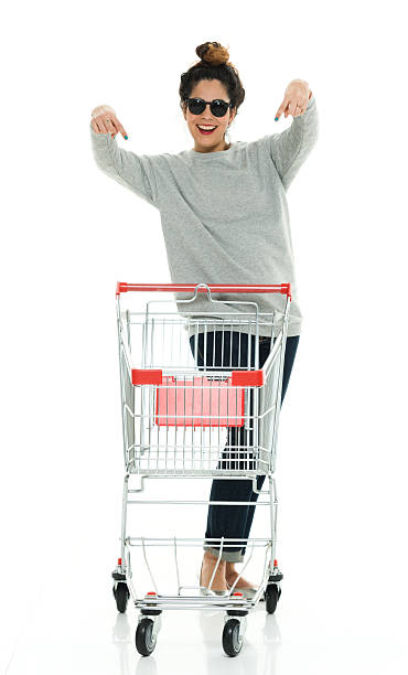 femme souriante pointant avec un panier d’achat - pull cart photos et images de collection