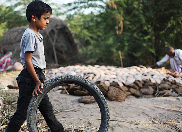 Rural boy and girl playing with tyre wheel on road