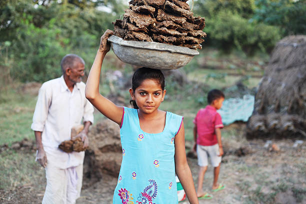 kleines armes mädchen trägt mistkuchen - poverty india child little girls stock-fotos und bilder