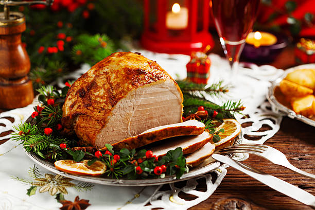 Christmas baked ham, served on the old plate. Christmas baked ham, served on the old plate. Spruce twigs all around. Front view. roast dinner photos stock pictures, royalty-free photos & images