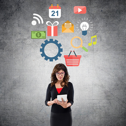 Young businesswoman standing in front of wall and working on digital tablet with infographic concept on wall.