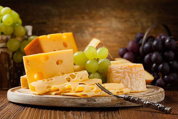Mix cheese on wooden board. Mix cheese on wooden board with grapes. Front view. gouda cheese stock pictures, royalty-free photos & images
