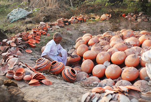 Indian potter preparing to remove the fired clay pots from the kiln at a pottery in Haryana/India. 
