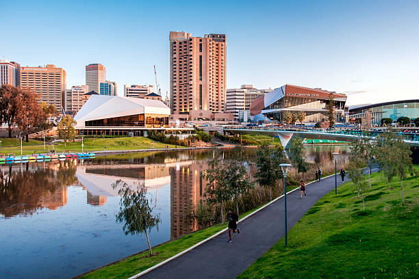 Torrens river bank in Adelaide Adelaide, Australia - September 11, 2016: Torrens river bank with people walking through foot bridge in Adelaide city centre at sunset adelaide stock pictures, royalty-free photos & images