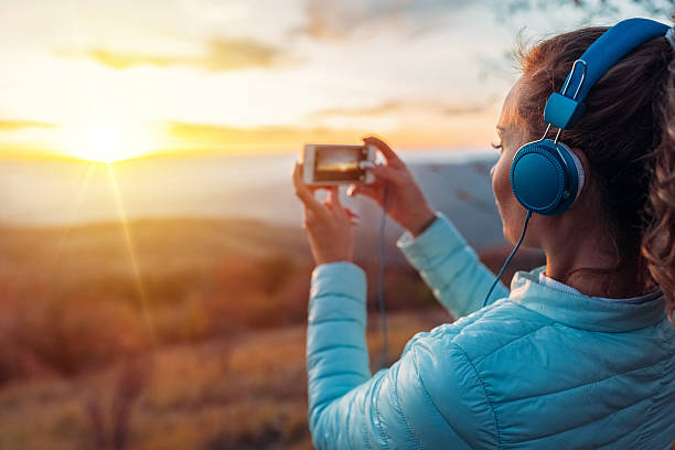 istock Young woman photographing the sunset 617773404