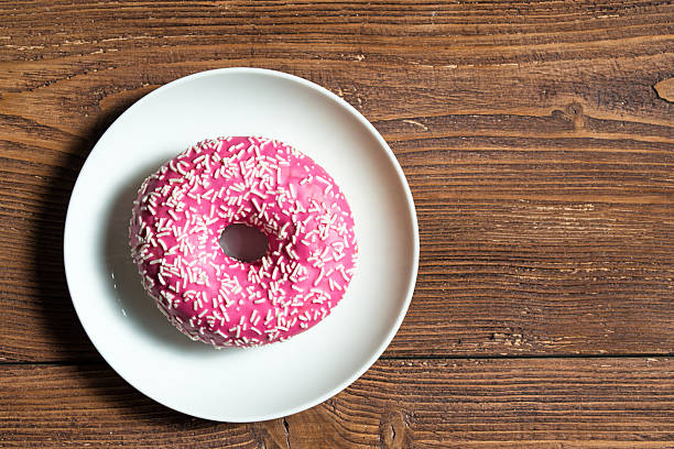istock Pink donut on a plate on wooden background 617773900