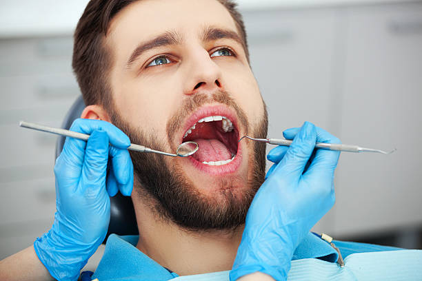 jeune homme faisant vérifier ses dents par un dentiste. - dentist dentist office dental hygiene dental equipment photos et images de collection