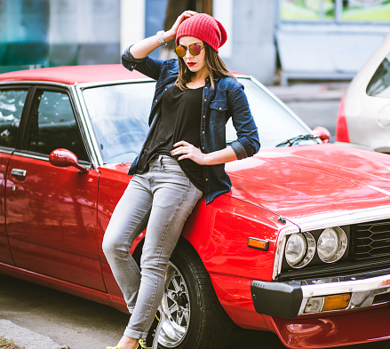Pretty stylish woman standing by the red retro car