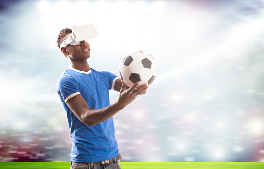 Young man with virtual reality headset or 3d glasses over football field on stadium background
