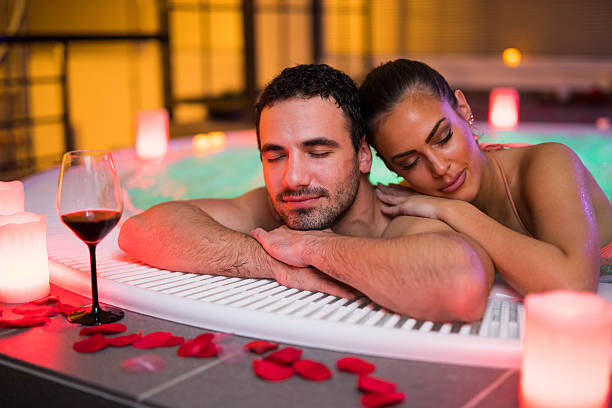casal carinhoso relaxando em banheira de hidromassagem em spa de saúde - couple hot tub spa treatment health spa - fotografias e filmes do acervo