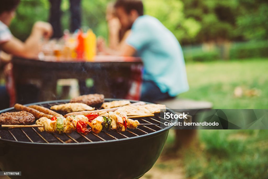 Time for barbecue Friends making barbecue and having lunch in the nature. Barbecue Grill Stock Photo