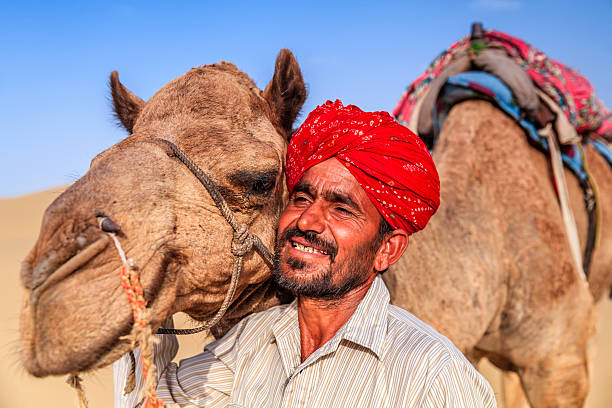 istock Indian man holding camel on sand dunes, Rajasthan, India 617863024