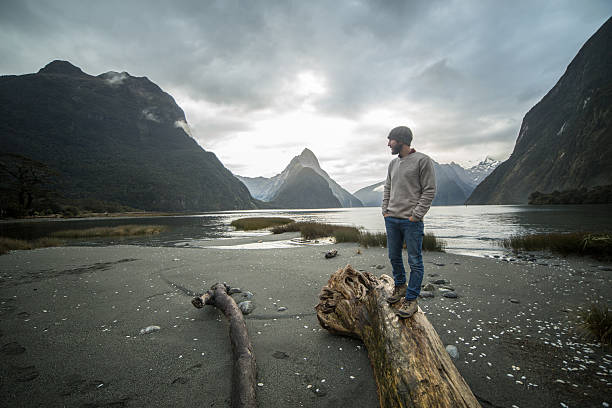 istock Lone man stands on log in mountains, looks at view 617863100