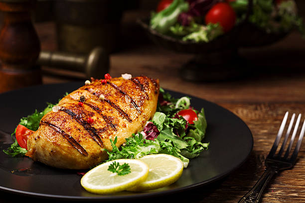 grilled chicken breast with green salad and french fries. grilled chicken breast with green salad and french fries on a black plate. grilled chicken breast stock pictures, royalty-free photos & images
