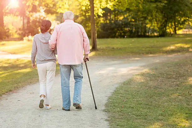 Senior woman and caregiver go walking outdoors