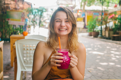Young Caucasian woman drinking smoothie   in cafe in Bangkok, Thailand 