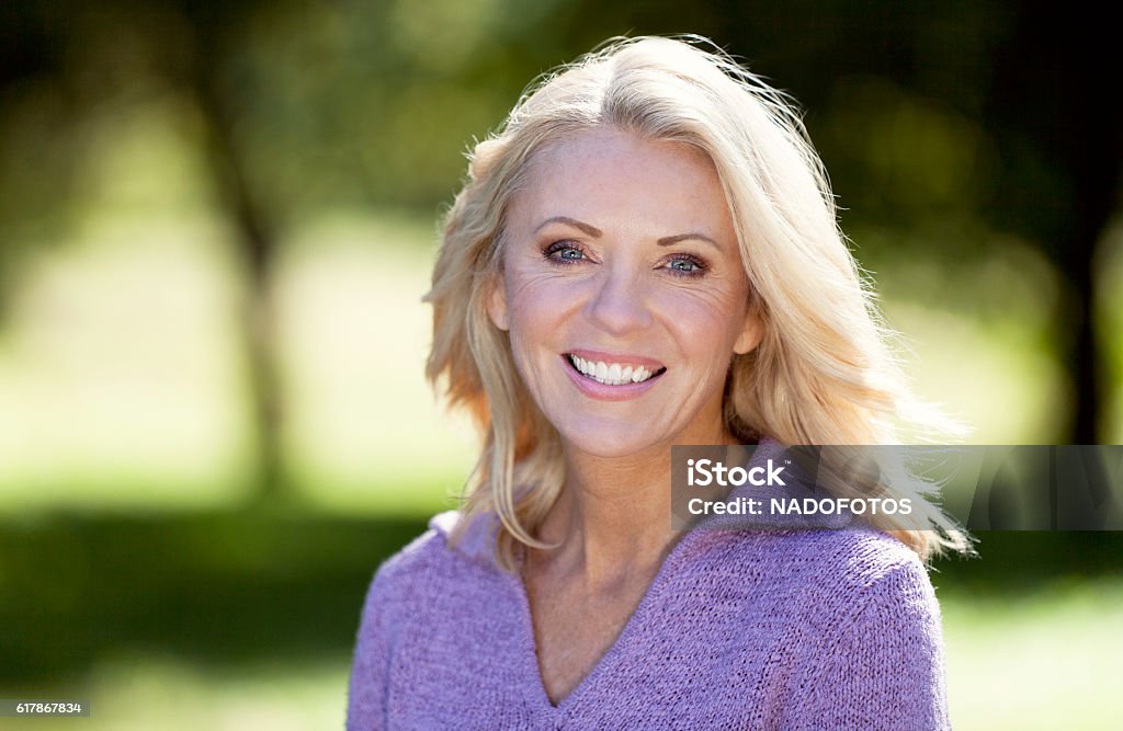 Retrato de una mujer madura sonriendo a la cámara en el parque - Foto de stock de Aire libre libre de derechos