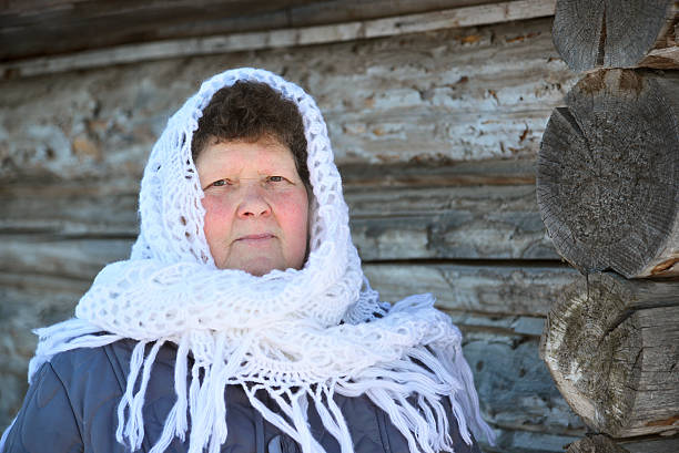 donna russa a scialle riscalda le mani vicino a un izba - izba foto e immagini stock