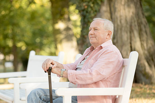 istock Senior man sitting on bench outdoors 617871834