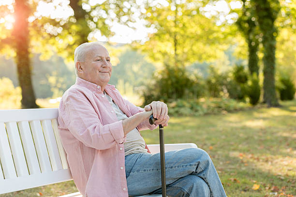 istock Senior man sitting on bench outdoors 617872886