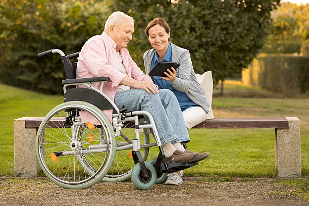 opiekun i starszy mężczyzna na ławce w parku, za pomocą cyfrowego tabletu - nursing home senior adult home caregiver physical therapy zdjęcia i obrazy z banku zdjęć