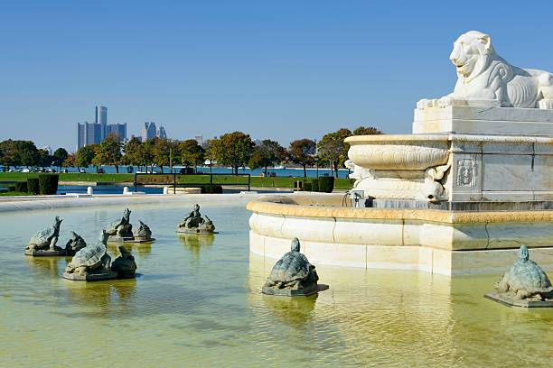 Closeup picture of a water fountain in a city park on a background of green trees