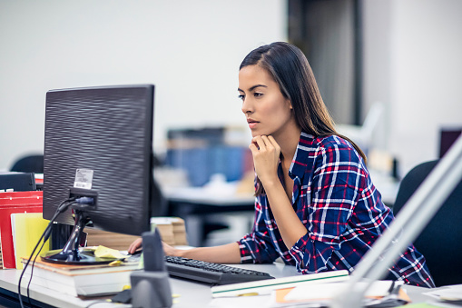 Young business woman sitting at her desk and working on computer in office