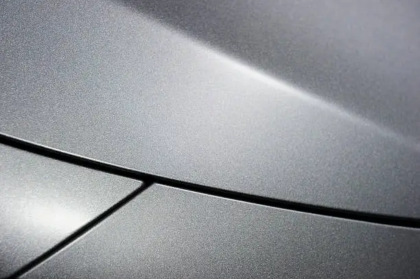 Surface of silver sport sedan car, detail of metal hood and fender of vehicle bodywork