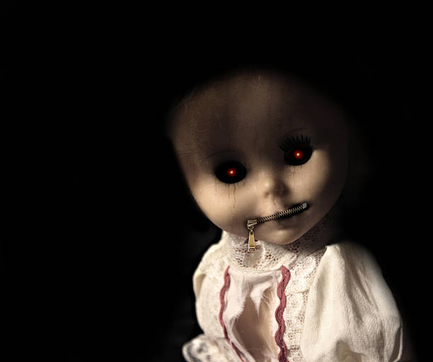 Vintage evil spooky doll with zipped mouth. On black background