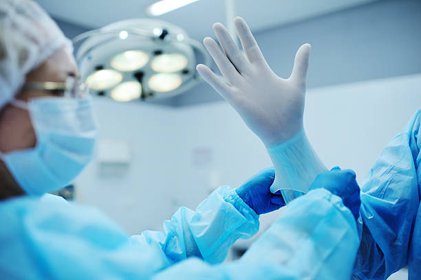 istock Assistant helps the surgeon put on latex gloves 617887612