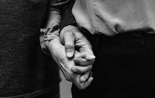 Close up detail of Elderly Old couple holding hands together, Monochrome