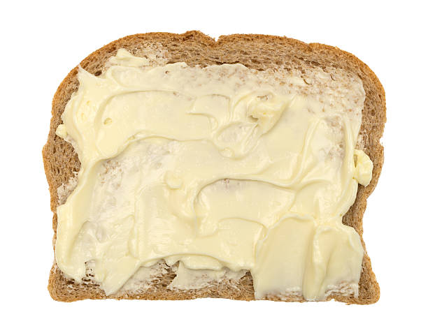 Top view of a slice of wheat bread with mayonnaise and margarine isolated on a white background.
