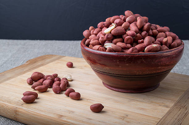 istock Old wooden cup filled with raw peanuts 617892150