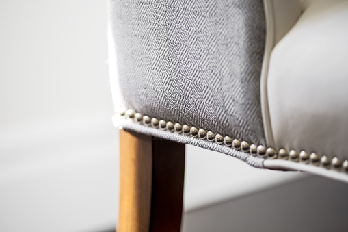 Horizontal close-up image of upholstered  white leather chair.