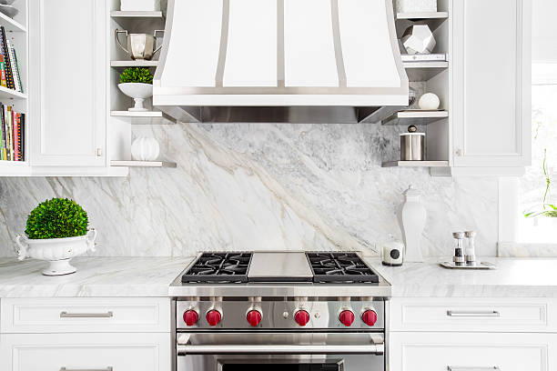 Bright Classic White kitchen with gas range Bright horizontal image of classic white kitchen, with gas range and marble backsplash. kitchen hood stock pictures, royalty-free photos & images