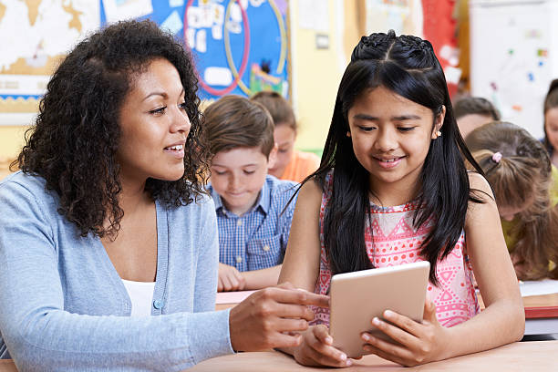 istock Teacher Helping Group Of Elementary School Children In Computer 617895340