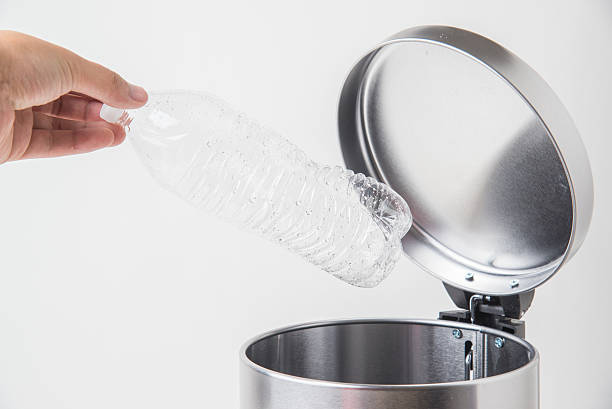 istock throwing away a bottle to trashcan 617897192