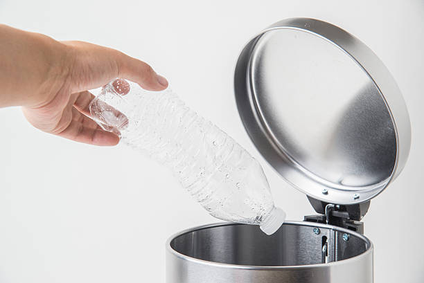 istock throwing away a bottle to trashcan 617897256