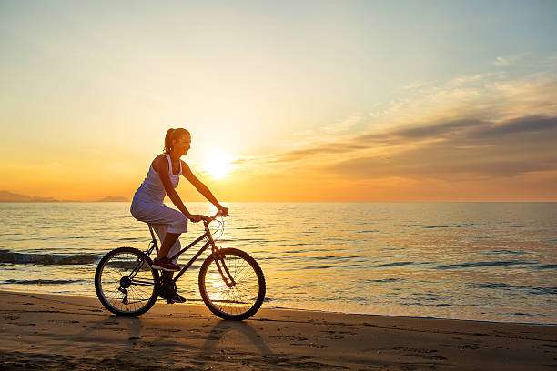 istock woman on vacation biking at beach 617897522