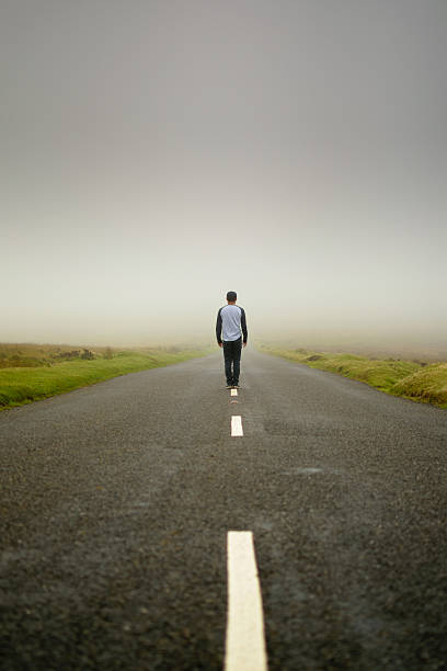 man in the middle of the road - decisions nature road street imagens e fotografias de stock