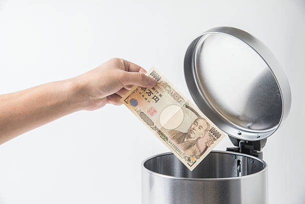 istock throwing away japanese yen  in trashcan 617897752