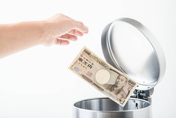 istock throwing away japanese yen  in trashcan 617897796