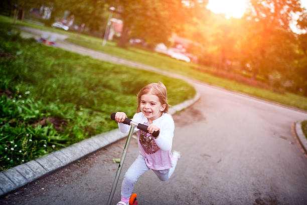 istock Girl riding push scooter 617906468