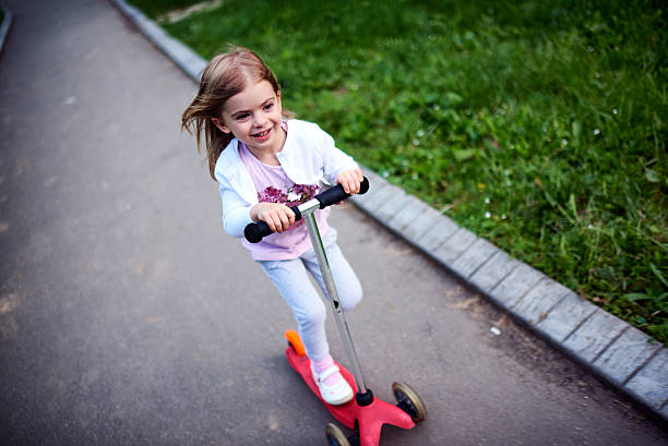 istock Girl riding push scooter 617906526