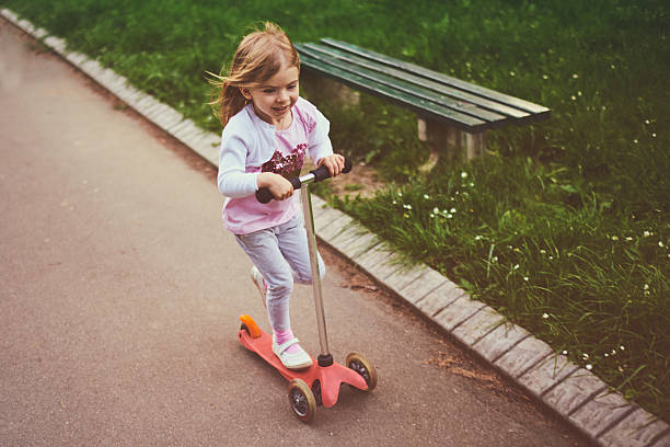 istock Girl riding push scooter 617906578
