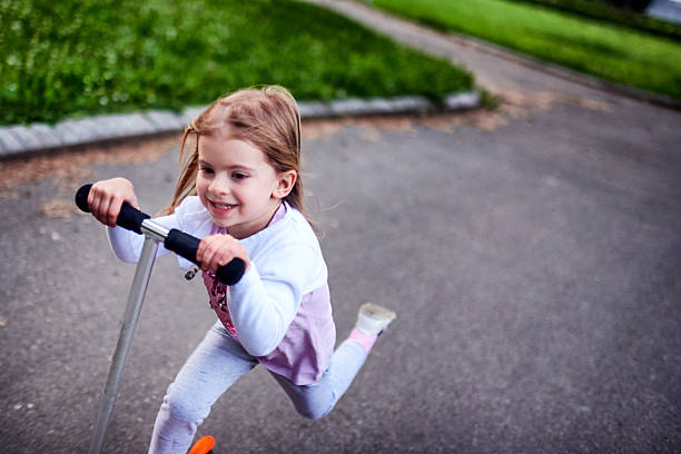 istock Girl riding push scooter 617906642
