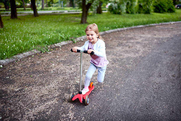 istock Girl riding push scooter 617906800