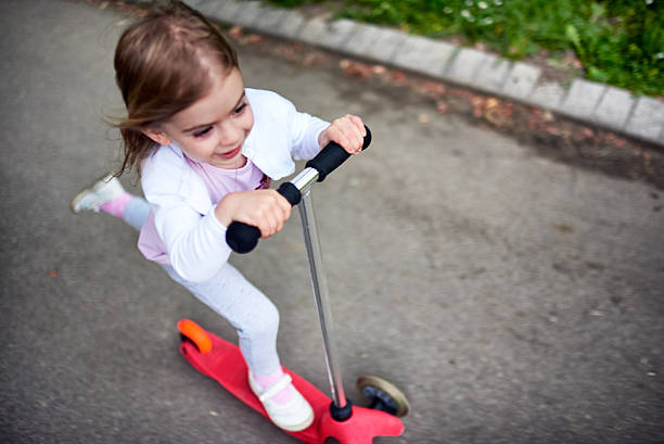 istock Girl riding push scooter 617906900