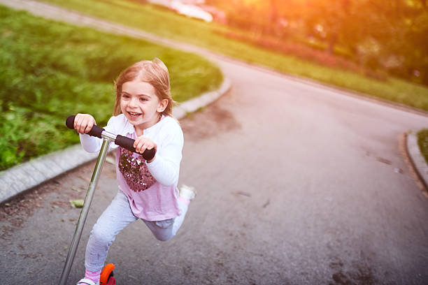 istock Girl riding push scooter 617906996